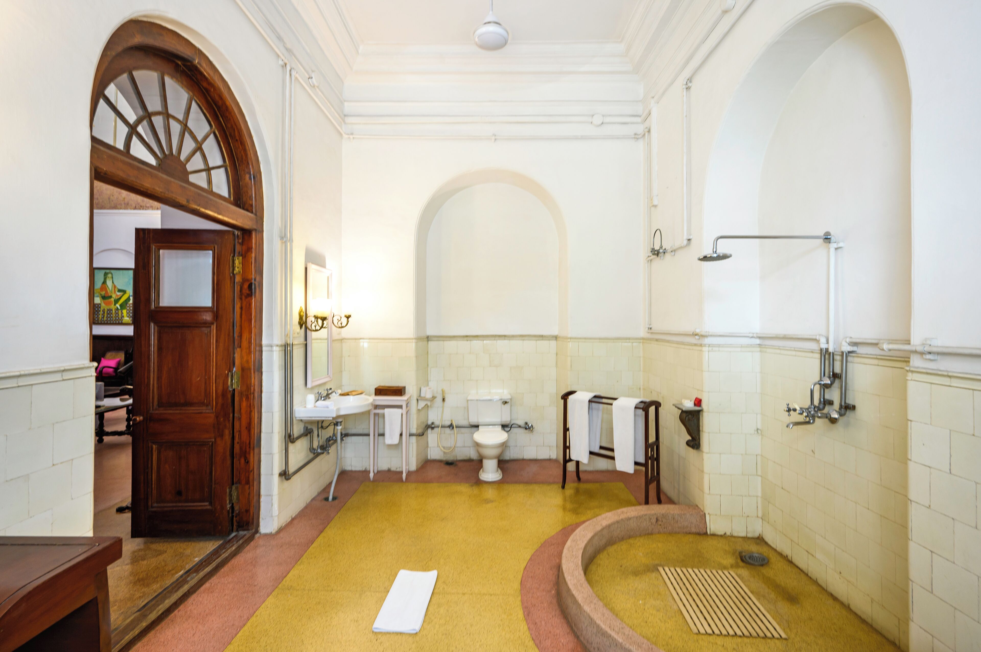 A bathroom with a wooden door, a sink, a toilet, and a shower area.