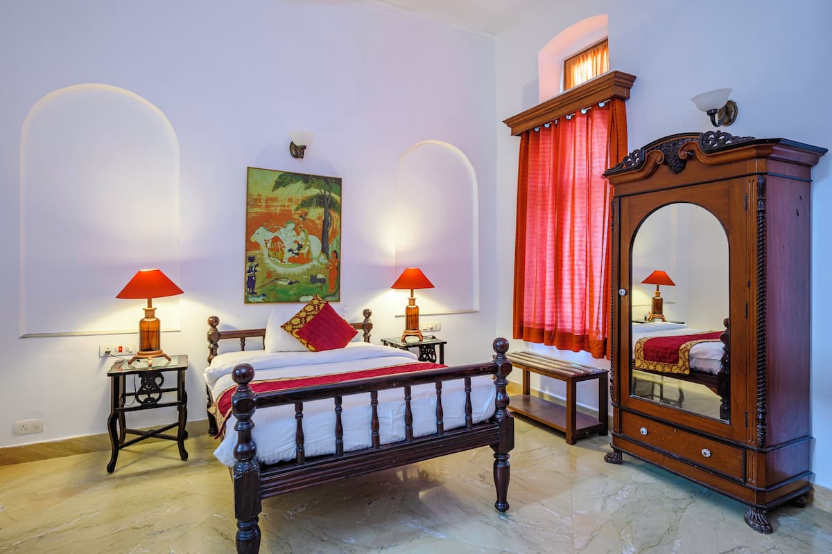 A bedroom with a wooden bed, two bedside tables with lamps, a large mirror, and a painting on the wall.