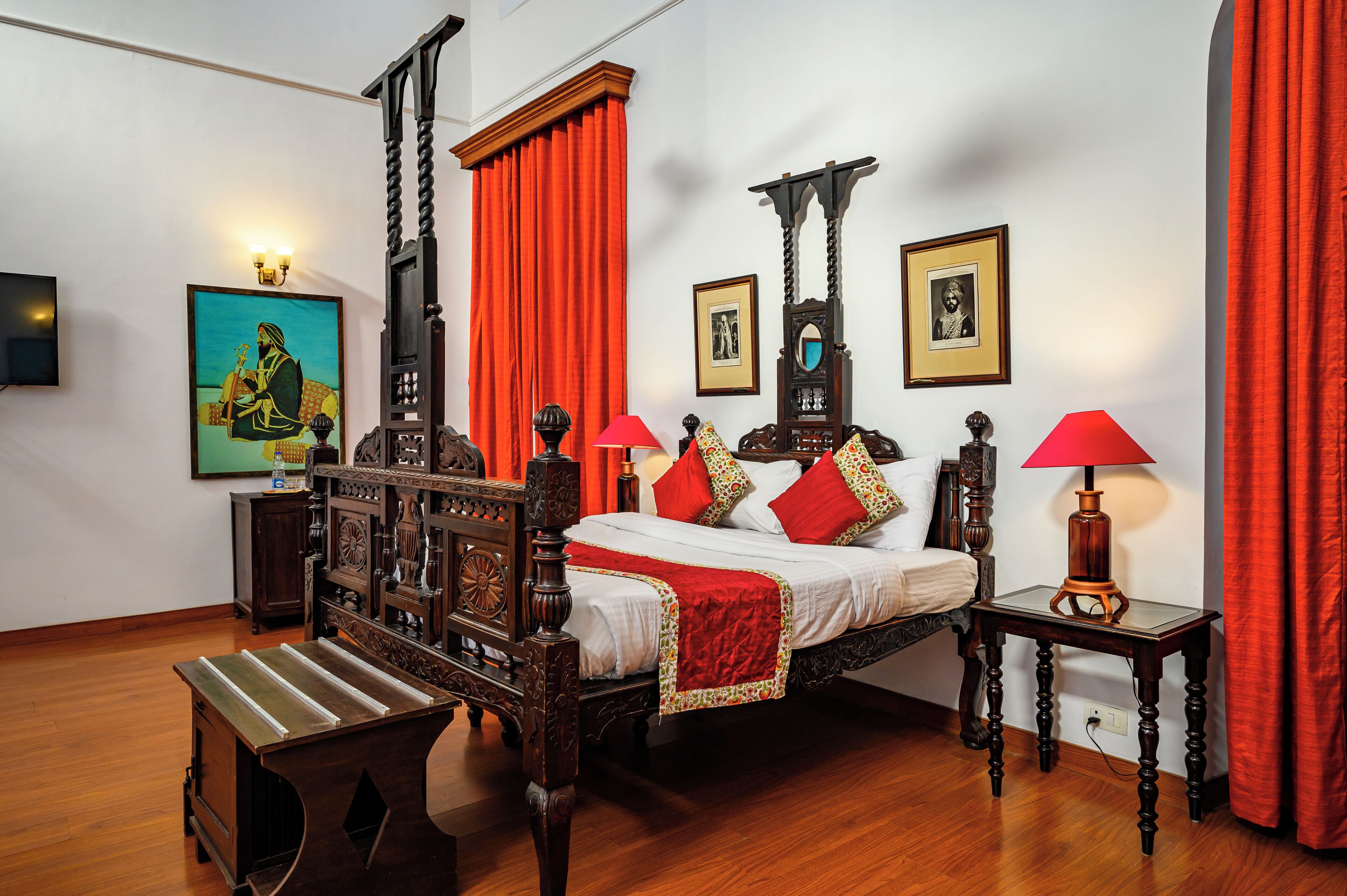 A four-poster bed with a canopy, a wooden bench, and two bedside tables with lamps.