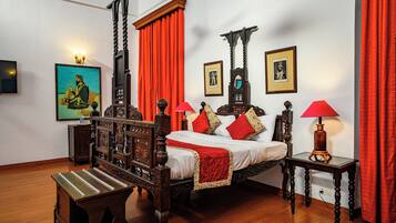 A four-poster bed with a canopy, a wooden bench, and two bedside tables with lamps.
