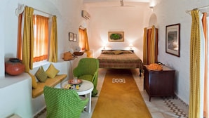 A cozy room with a bed, a small table, a chair, and a sofa. - Neemrana's - Hill Fort - Kesroli (Ramgarh)