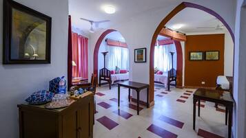 Una habitación de hotel con suelo a cuadros, muebles de madera y una zona de comedor con mesa y sillas.