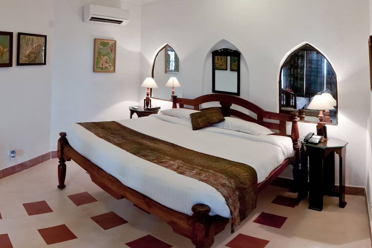 A neatly arranged bedroom with a wooden bed, two bedside tables with lamps, and three wall-mounted paintings.