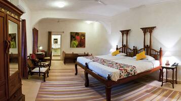 A bedroom with a large bed, wooden headboard, a desk, and a chair.