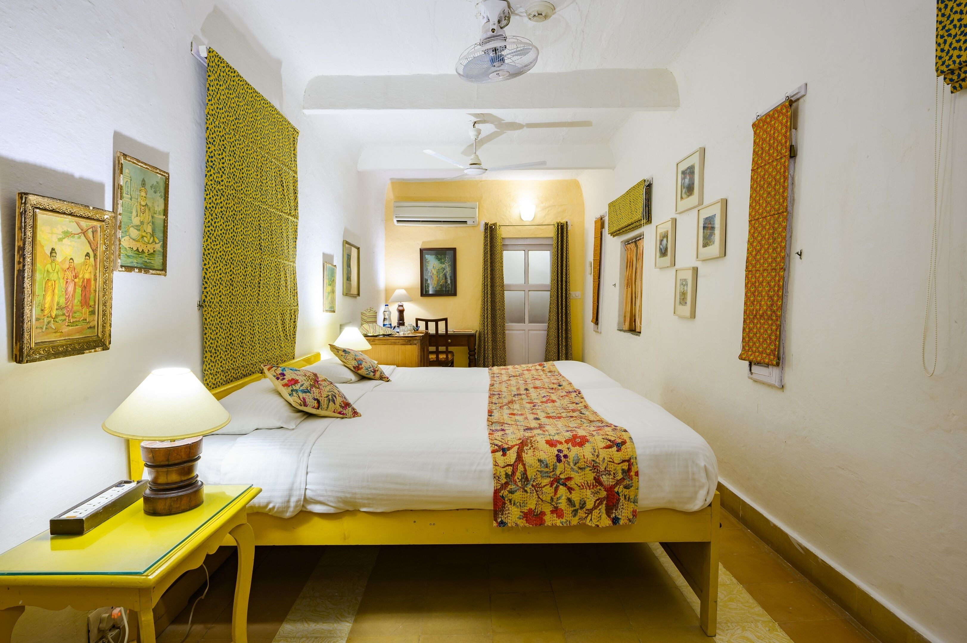 A bedroom with a bed, bedside table, lamp, and wall-mounted pictures.