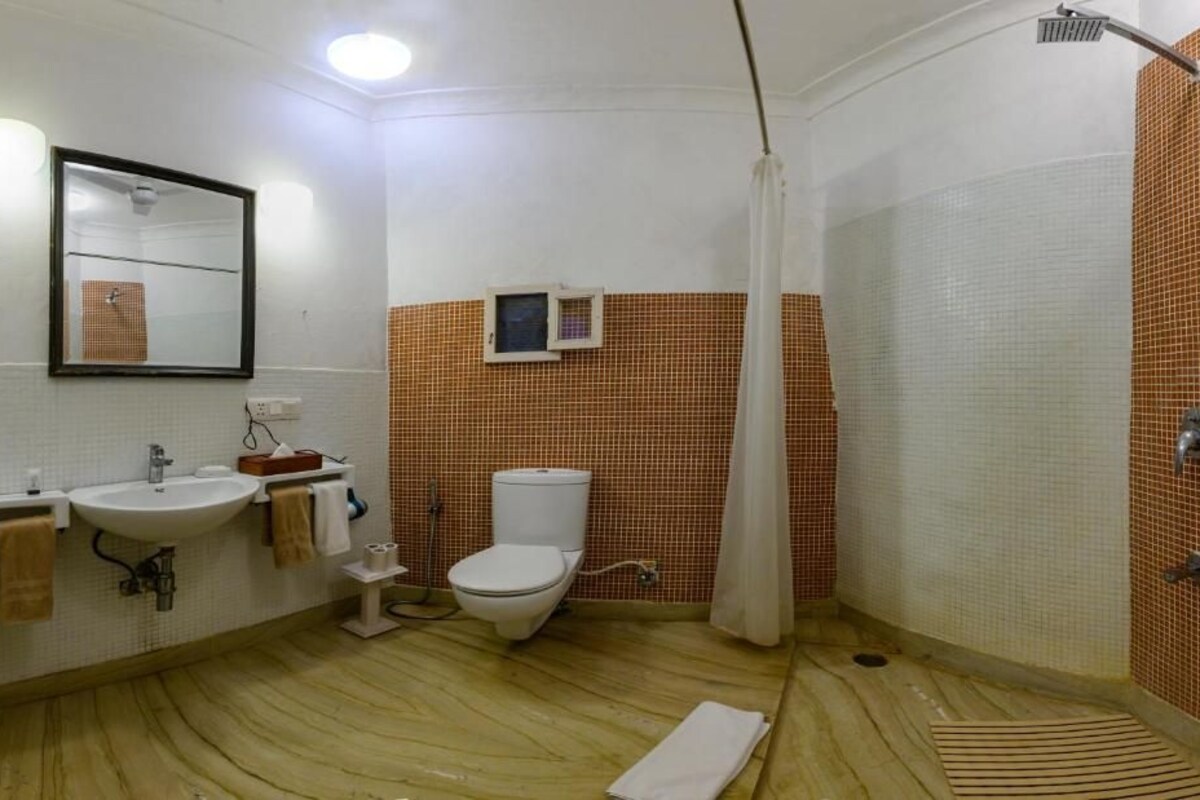 A bathroom with a sink, toilet, shower, and a mirror.
