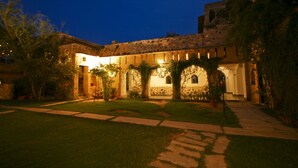 A courtyard with a stone building, a pathway, and greenery. - Neemrana's - Hill Fort - Kesroli (Ramgarh)