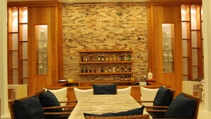 Zona de bar con pared de ladrillo, estantes de madera con botellas y mobiliario de mimbre.