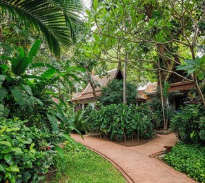 A pathway leading to a traditional building surrounded by lush greenery. - Anavana Beach Resort (Koh Samui)