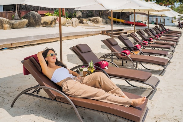 A beachside lounge area with sun loungers and umbrellas. - Anavana Beach Resort (Koh Samui)