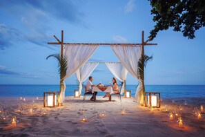 A beach setting with a canopy and tables set up for dining, overlooking the sea. - Anavana Beach Resort (Koh Samui)