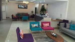 Un moderno vestíbulo de hotel con mostrador de recepción, sofás y una mesa de centro.