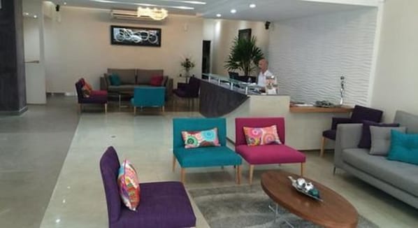 A modern hotel lobby with a reception desk, sofas, and a coffee table. - Columbia Palace (Buenos Aires)