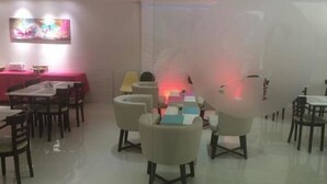 Un comedor con mesas y sillas, un mantel rosa y un cuadro en la pared.