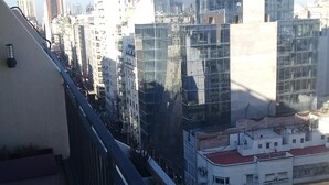Un balcón con vistas a un paisaje urbano, con edificios modernos y cielo despejado.