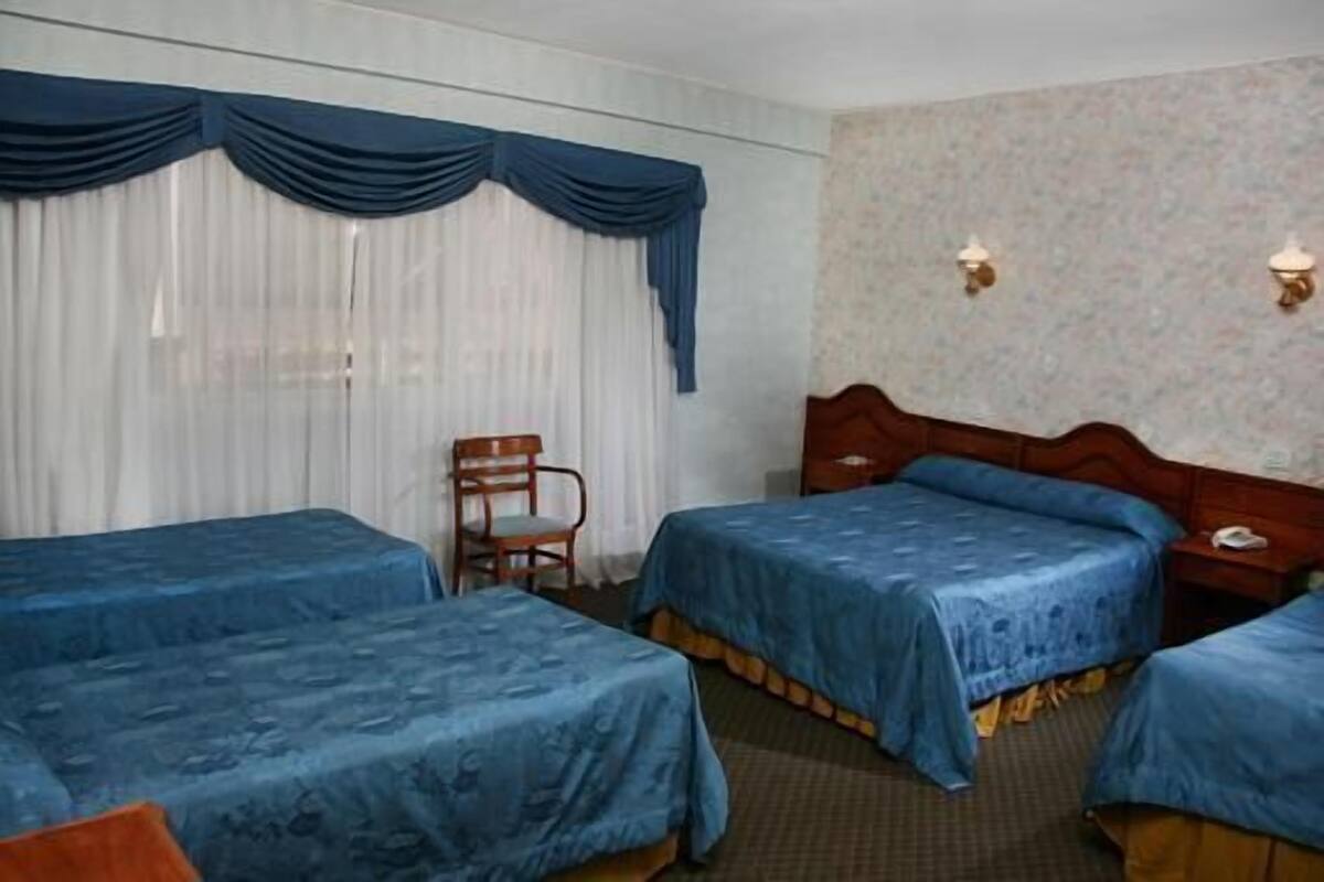 Habitación de hotel con dos camas, una silla y una mesita de noche con teléfono.
