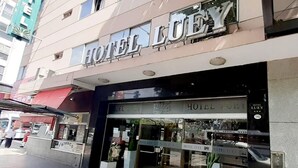 Entrada de un hotel con fachada de vidrio y señalización que dice "HOTEL LUEY".