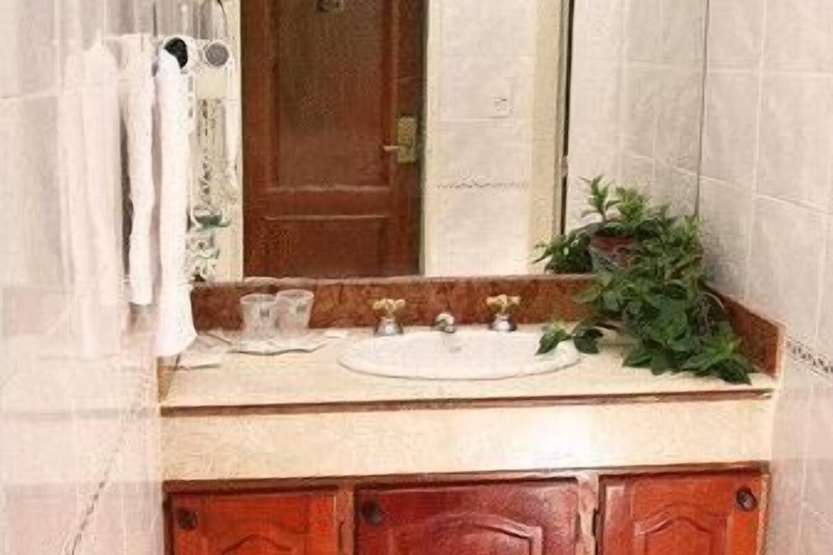Un baño con tocador de madera, un espejo y cortina de ducha.