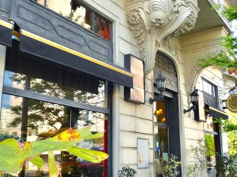 Un edificio con detalles arquitectónicos ornamentales, incluyendo un arco decorativo y un toldo negro sobre la entrada.