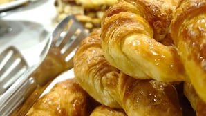 A buffet with various food items, including a selection of pastries and a vase with flowers. - Hotel Benevento (La Plata)
