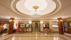 A spacious lobby with a grand chandelier, a reception desk, and seating areas. - Astor Hotel (MAR DEL PLATA)