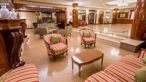 A spacious lobby with striped armchairs, a wooden coffee table, and a chandelier. - Astor Hotel (MAR DEL PLATA)