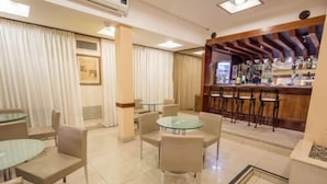 A hotel lobby with a bar area, round tables, and chairs. - Astor Hotel (MAR DEL PLATA)