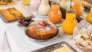 A buffet table with various food items including pastries, fruits, and beverages. - Estocolmo Hotel (Mar del Plata)
