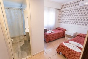 A room with a shower, two beds with red bedding, a white nightstand, and a wall with circular patterns. - Estocolmo Hotel (Mar del Plata)