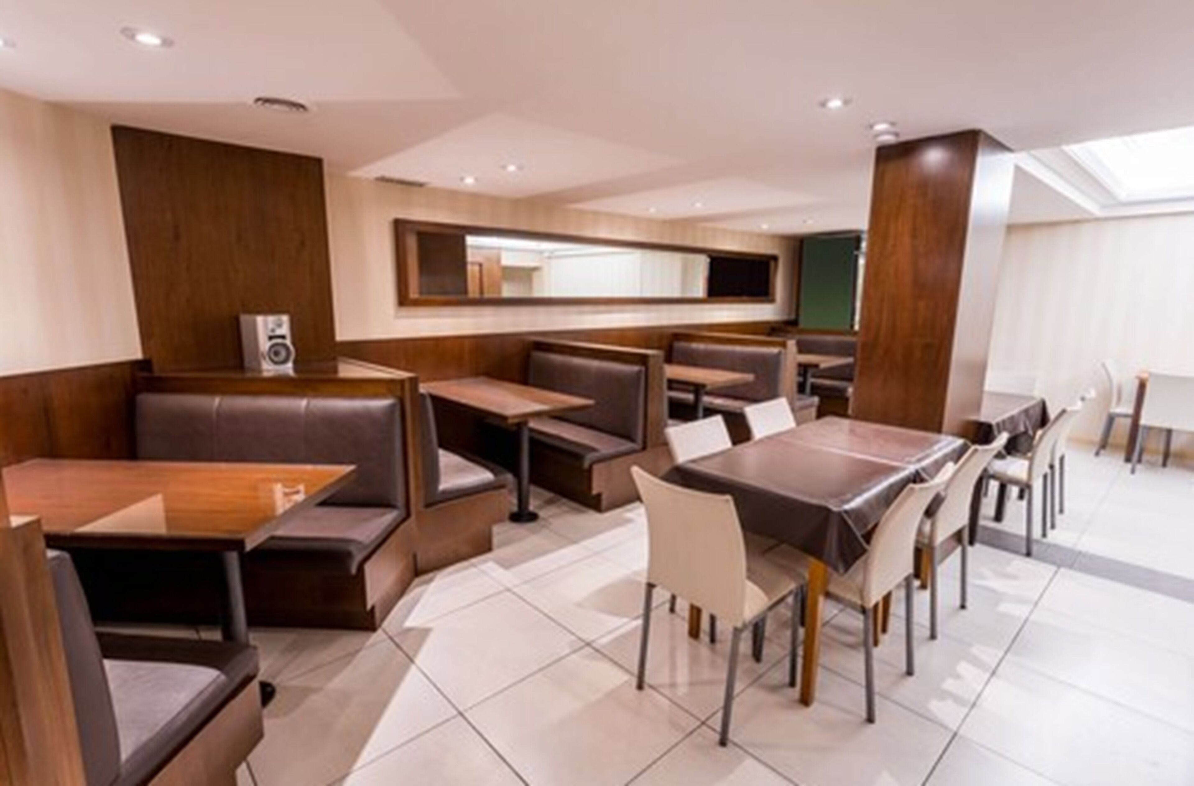 A modern restaurant with booth seating and rectangular tables.