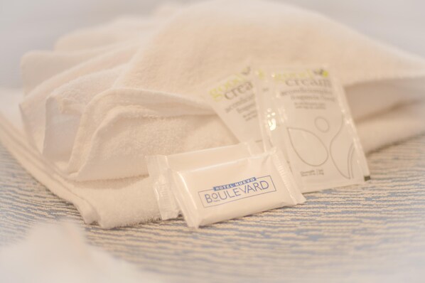 A white towel and two packets of Hotel Boulevard cream on a striped surface.