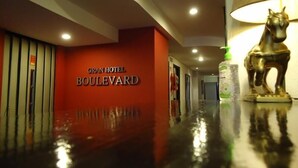 Un couloir d’hôtel avec un sol ciré, une enseigne indiquant « GRAN HOTEL BOULEVARD » et une statue de cheval.