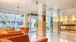 Un moderno vestíbulo de hotel con sofás a rayas, un mostrador de recepción y grandes ventanales con vistas a la calle.