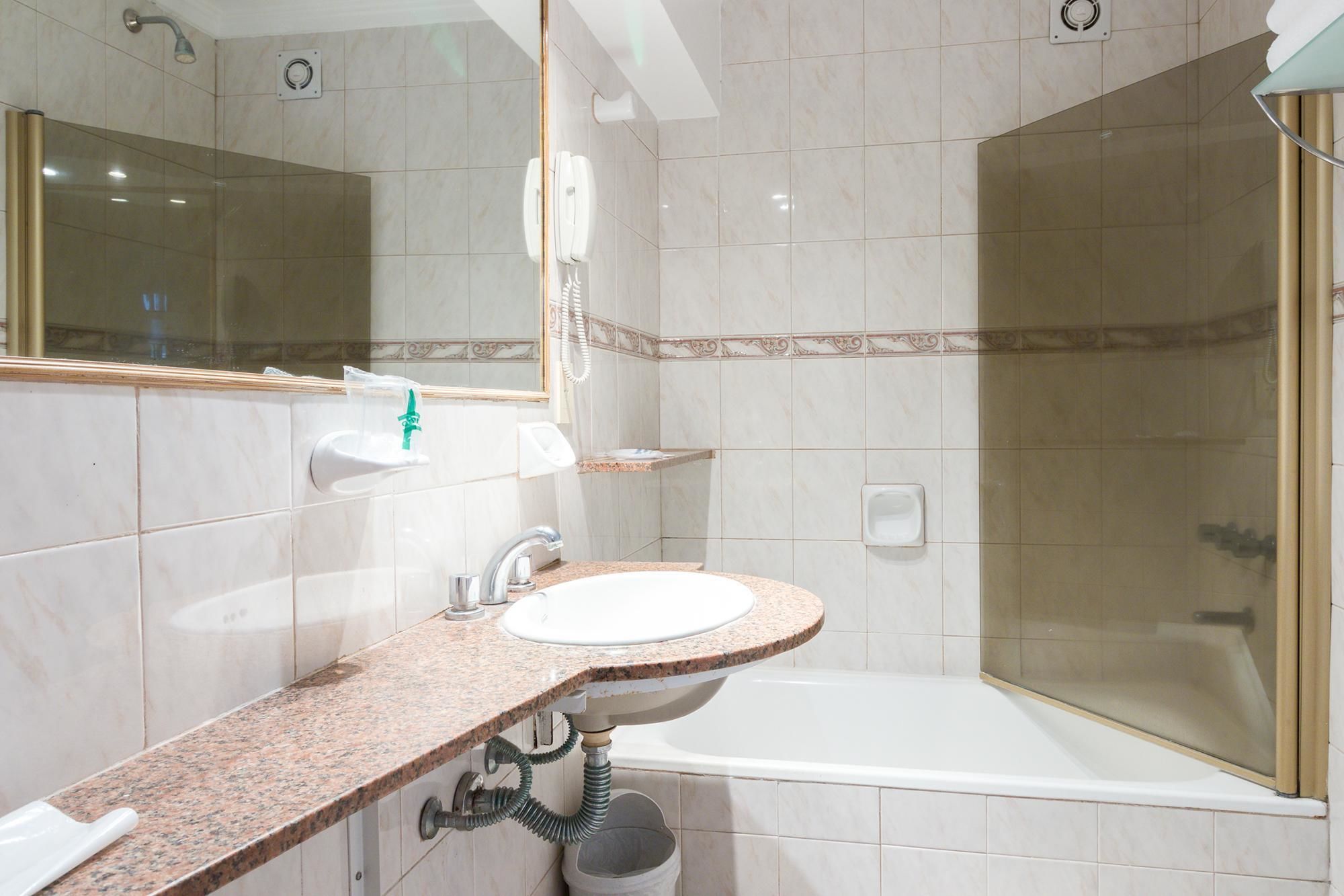 A bathroom with a sink, mirror, and shower.