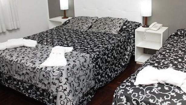 A hotel room with a double bed, two bedside tables, and a nightstand with a phone.