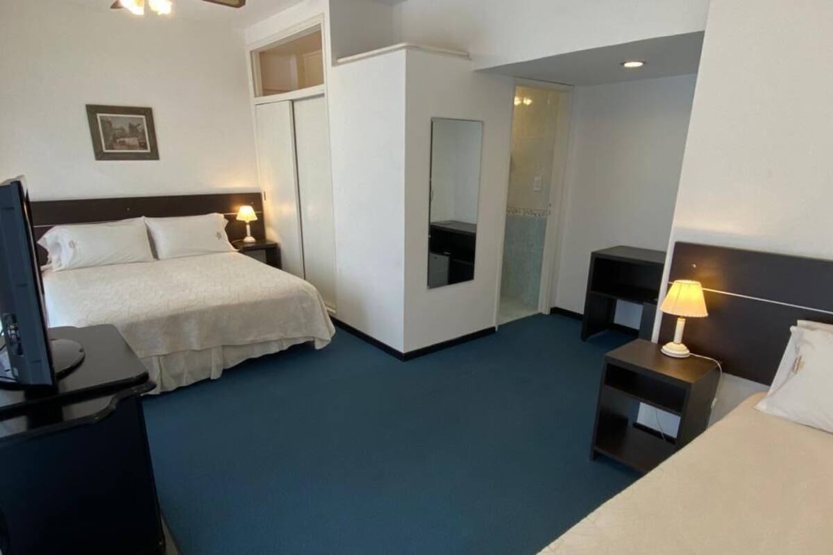 Ein Hotelzimmer mit Bett, Fernseher, Schreibtisch und Spiegel.