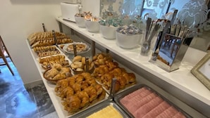 A buffet area with various food items, including pastries and meats, arranged on a counter. - Montecarlo Hotel (Mar del Plata)