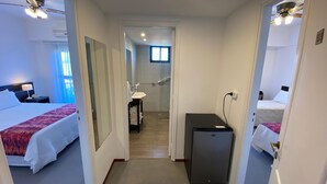 A hotel room with two beds, a desk, a small refrigerator, and a bathroom visible through an open door. - Montecarlo Hotel (Mar del Plata)