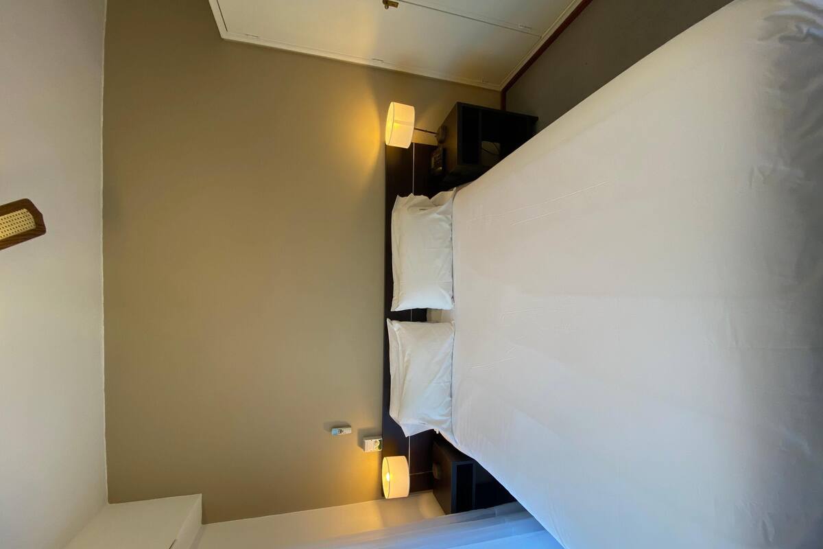 Ein Hotelzimmer mit einem Bett, Nachttischlampen und einem Nachttisch.