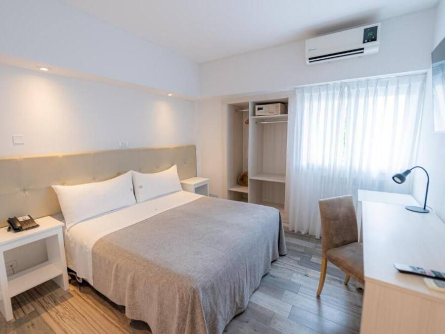 A hotel room with a bed, bedside table, desk, chair, and a wardrobe.