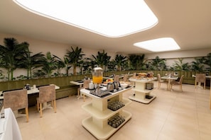A modern breakfast area with multiple seating arrangements, a central buffet table, and a variety of breakfast items. - Sennac Hotel (Mar del Plata)