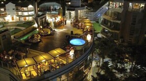 A rooftop bar with a pool, surrounded by outdoor seating and a view of the cityscape.