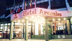 The exterior of Hotel Arenales with a prominent entrance and multiple flags. - Arenales Hotel (San Fernando del Valle de Catamarca)