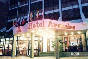 Exterior del Hotel Arenales, con una entrada destacada y varias banderas.