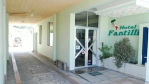 A hotel entrance with a stone-paved pathway leading to a glass door. - Hotel Fantilli (Puerto Madryn)