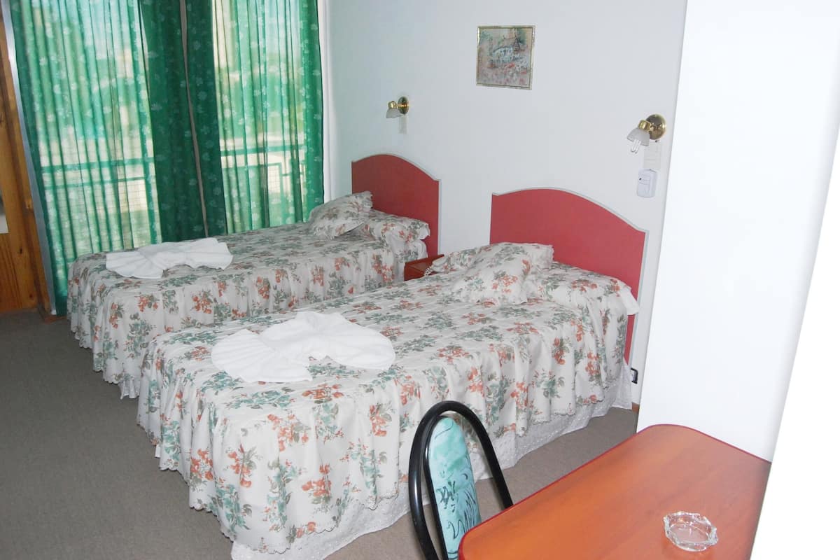 A room with two single beds, a wooden chair, and a small table.