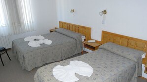 A hotel room with two single beds, a wooden headboard, a bedside table with a phone, and a radiator on the wall. - Hotel Fantilli (Puerto Madryn)
