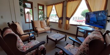 Una sala de estar con sofá, sillones, una mesa de centro y televisor.