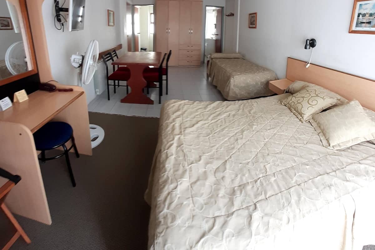 Une chambre d’hôtel comprenant un lit, un bureau, une chaise, une armoire et un miroir.
