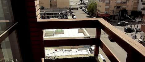 A balcony with a view of a cityscape, including buildings and a clear sky.